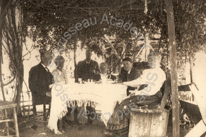 Image of Polhemus family memebrs having lunch under a vine-covered arbor