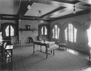 Image of View of living room with piano and table in center and fireplace at the far end